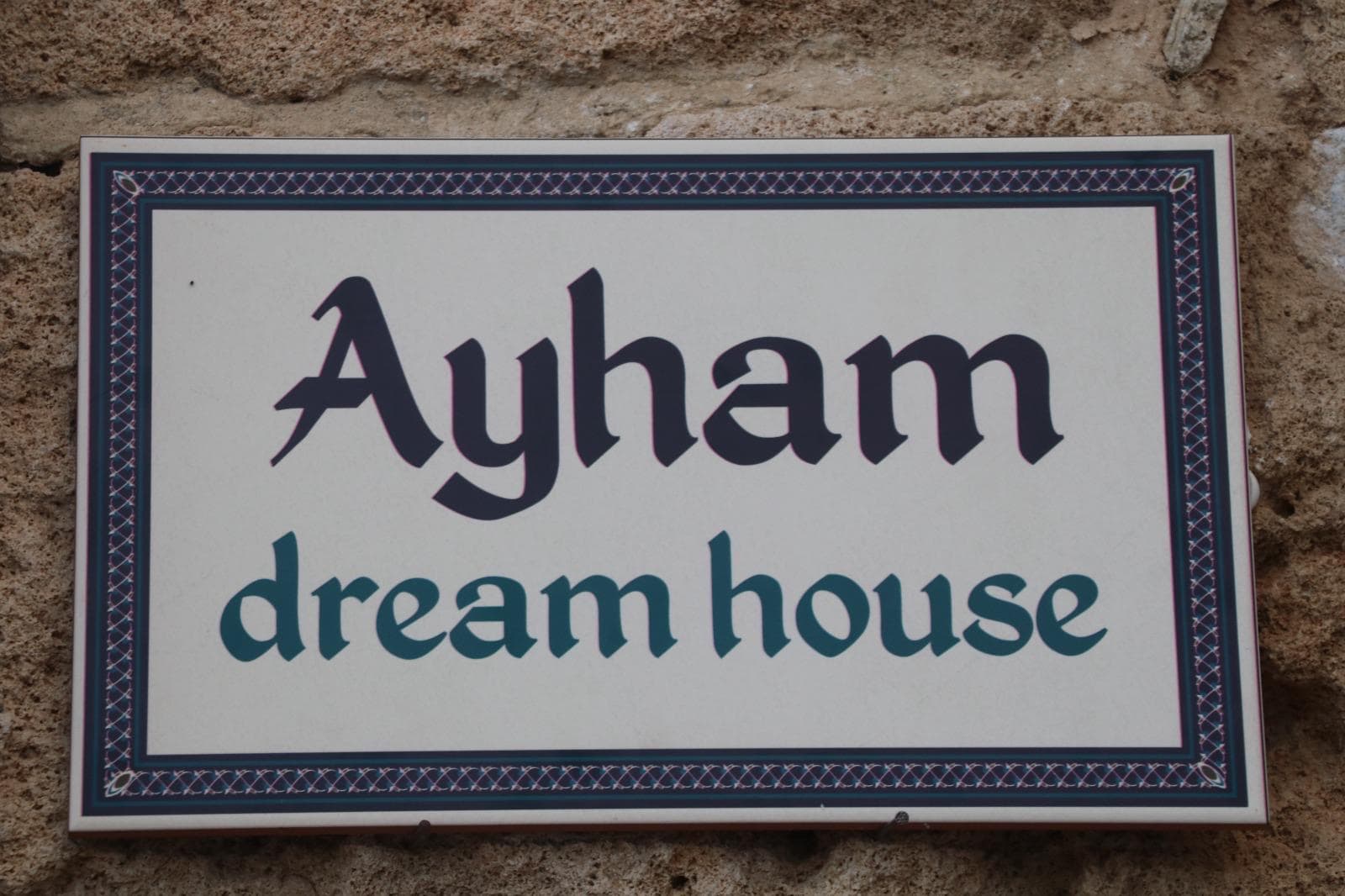 שלט "Ayham Dream House" על קיר אבן חיצוני